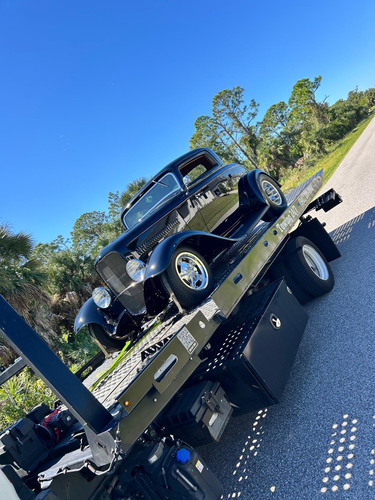 A classic hot rod loaded on the flatbed, low and dark